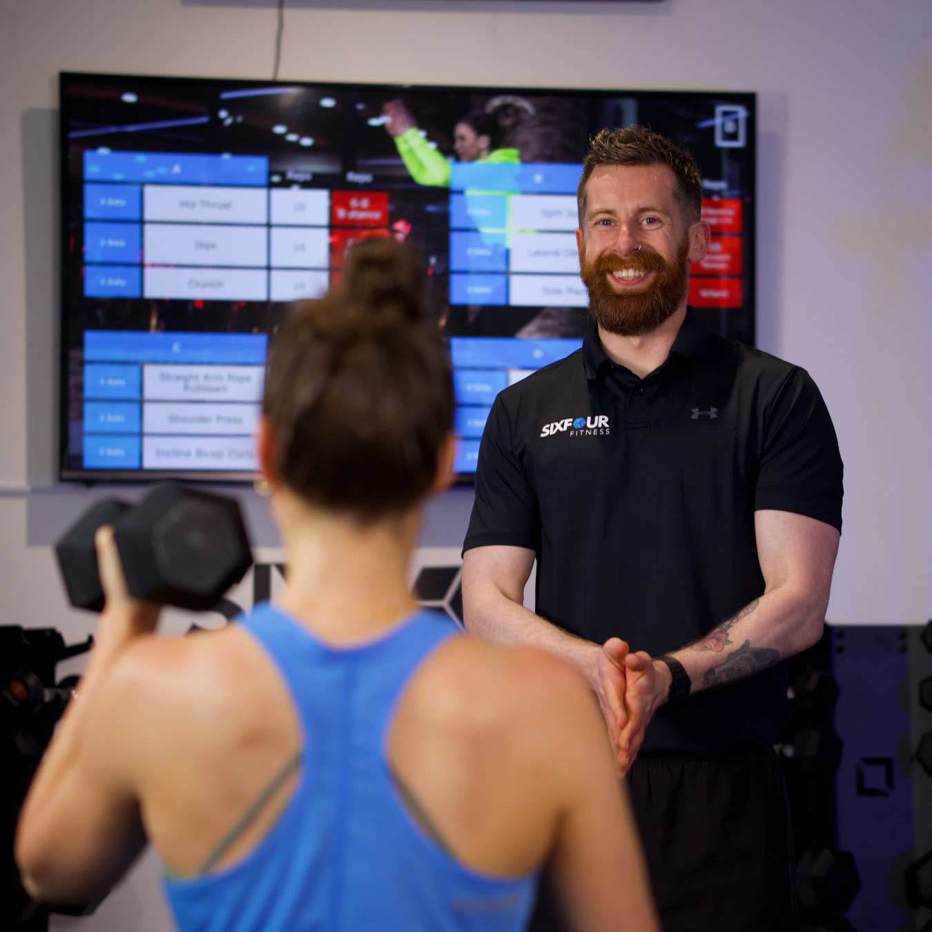 A SixFour Fitness coach guiding a member through her session